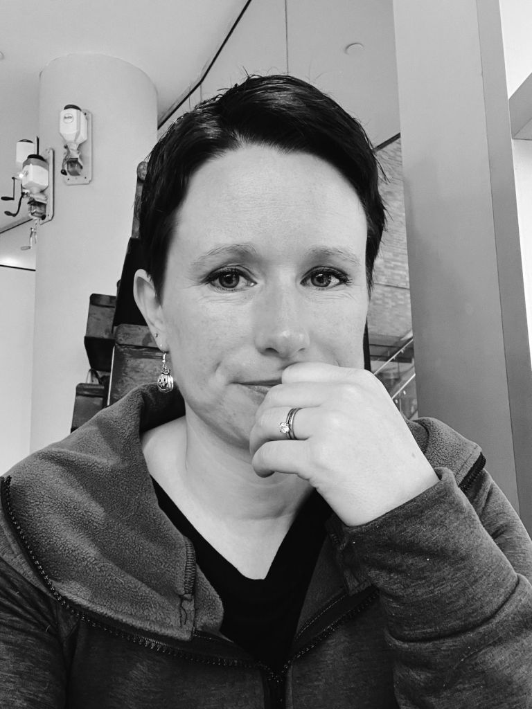 Black and white photo of Kim looking resigned, with her hand in front of her mouth.